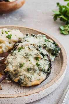 a plate topped with potatoes and spinach covered in gravy on top of a table