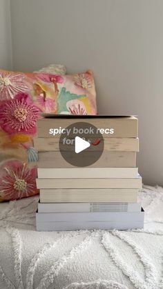 a stack of books sitting on top of a bed next to a pillow and pillows