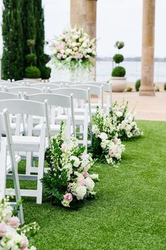 rows of white chairs with flowers on them