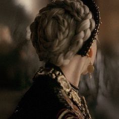 the back of a woman's head with braids in her hair and earrings