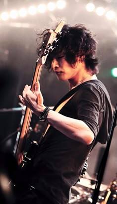 a man holding a guitar while standing on top of a stage