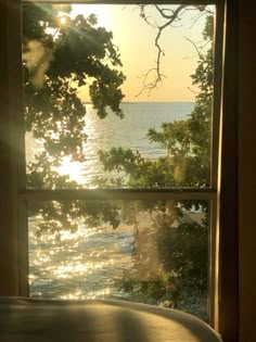 the sun is shining through an open window overlooking the water and trees in front of it