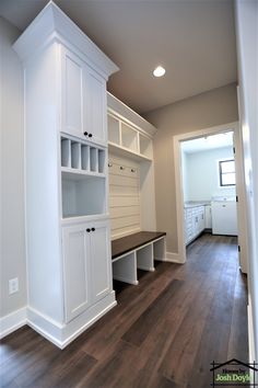 an empty room with white cabinets and wood floors