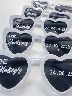 heart shaped sunglasses with the names of their guests and date written on them in white frames