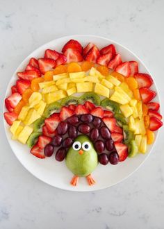 a white plate topped with fruit and a turkey made out of cut up strawberries