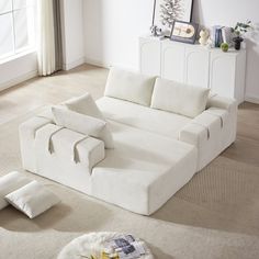 a large white couch sitting on top of a carpeted floor next to a window