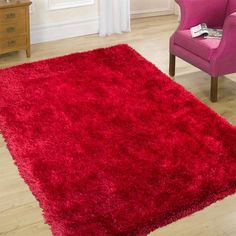 a bright red rug is on the floor in front of a pink chair and window