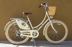 a white bicycle parked next to a wall with a basket on the handlebars