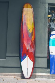 the surfboard is leaning up against the wall next to another board that has been painted red, white, and blue