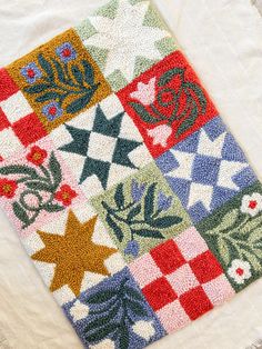 a colorful patchwork quilt with stars and flowers on it's side, sitting on a white surface