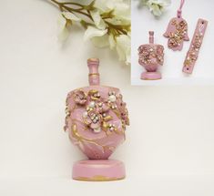 a pink vase sitting on top of a table next to two pieces of jewelry and flowers