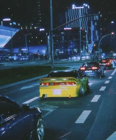 cars are driving down the street at night in an urban area with tall buildings and skyscrapers