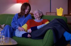 two women sitting on a green couch smiling