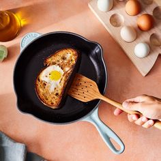 someone is frying an egg in a skillet on the table next to eggs