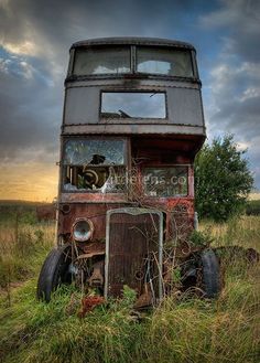 an old bus sitting in the middle of a field