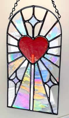 a stained glass window with a heart hanging from it's center and chain around the edges