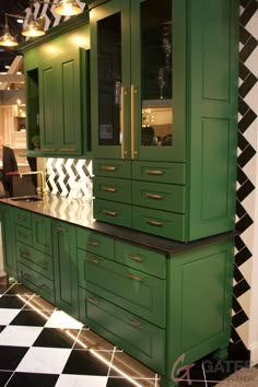 a kitchen with green cabinets and black and white checkered flooring on the walls