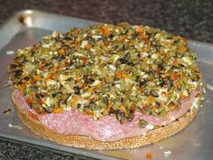 a meatloaf on a bun with toppings is sitting on a baking sheet