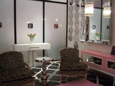 two chairs and a table in a room with mirrors on the wall, one chair has leopard print upholstered armrests