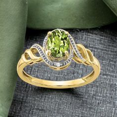 a yellow gold ring with an oval cut peridolite surrounded by white and green diamonds