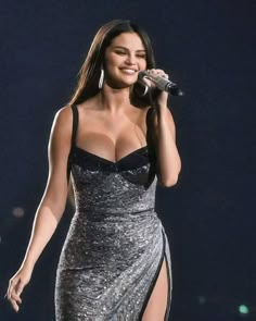 a woman in a silver dress holding a microphone