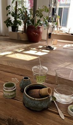 there are some cups and spoons on the wooden table next to each other with water in them