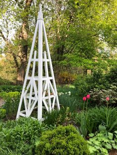 a tall white sculpture sitting in the middle of a garden