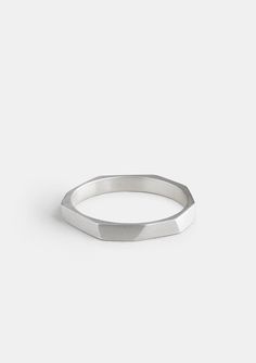 a silver ring on a white surface with a small diamond cut out in the middle