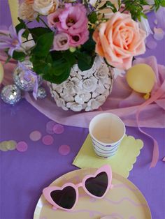 the table is set with pink and white flowers, sunglasses, napkins, and confetti