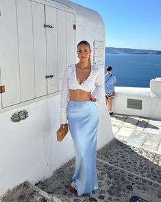 Discover stunning dinner party outfit ideas perfect for your vacation in Greece, just like this classy summer outfit with a light blue silk midi skirt and a white long sleeve top! Whether you're exploring the picturesque streets of Mykonos, lounging on the beaches of Santorini, or enjoying the nightlife in Crete, these Euro summer looks are guaranteed to keep you chic and comfy.