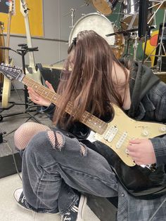 a woman sitting on the floor playing an electric guitar