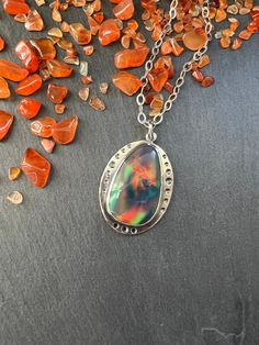 "This stone is a man made aurora borealis opal.  It has very interesting multicolored color play that reminds me of a galaxy inside.   The pendant is made with sterling silver and the stone is set in a bezel setting. NOTE:  As with all opal, this is a soft stone so care will need to be taken to not scratch or damage it.  Always remove your jewelry prior to washing and showering.  Jewelry should always be the last thing you put on after applying makeup, perfume, hairspray, etc.  Never wear soft stone jewelry while working out, or to bed, as this my cause unnecessary wear and tear and my damage the stone. Total length of the pendant is 38mm (approximately 1.5\"). Width is 28mm (approximately 1.13\"). When purchasing you have the option to purchase the pendant only or with your choice of chai Mystical Silver Jewelry With Large Stone, Silver Celestial Multi-stone Jewelry, Celestial Silver Oval Necklace, Silver Celestial Jewelry With Oval Cabochon, Silver Opal Gemstone Jewelry, Silver Multi-stone Celestial Jewelry, Unique Iridescent Gemstone Necklaces, Silver Oval Celestial Necklace, Unique Iridescent Gemstone Necklace