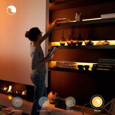 a woman standing in front of a fire place with candles on the shelves above her