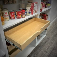 an open drawer in a pantry filled with canned food