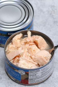 a can of tuna with a spoon in it next to a can of canned fish