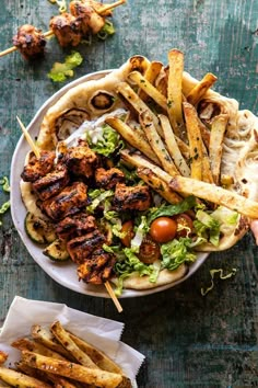 a plate filled with chicken and french fries on top of a table next to a bowl of food