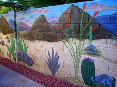 a mural on the side of a building with cactus and mountains painted on it's sides