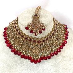 Beautiful antique gold necklace set with dazzling champagne zircon crystals and maroon stones. Plus maroon glass beads. Perfect bridal set Comes with matching jhumka earrings and matching tikka! Necklace 3 inch with adjustable string Earrings 2.25 Inch including jhumka length x 1 inch width Tikka 2.5 inch pendant plus 2 inch chain and 2 inch extender chain  Ready to be shipped ❤️ Festive Crystal Jewelry With Intricate Design, Bollywood Style Wedding Jewelry With Stones, Traditional Crystal Jewelry With Stone Work, Ornate Jeweled Necklaces For Wedding, Ornate Jeweled Wedding Necklaces, Celebration Ruby Jewelry With Stone Work, Festive Crystal Jewelry With Stone Work, Ruby Jewelry Sets With Stone Work For Celebration, Celebration Ruby Jewelry Sets With Stone Work