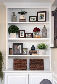 a white book shelf filled with pictures and plants