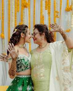 two women dressed in green and white standing next to each other with their hands up