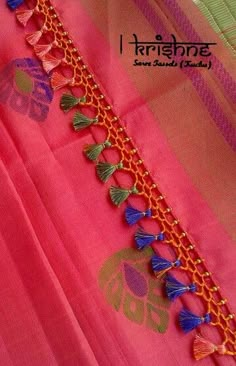 an orange and pink saree with tassels on it