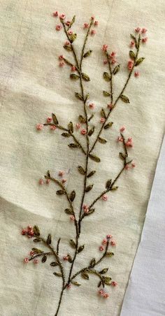 an embroidered piece of cloth with small pink flowers on the top and bottom of it