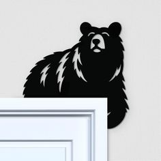 a black bear is standing next to a white door