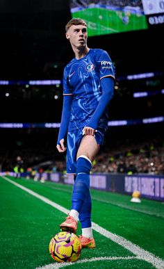 a soccer player is standing on the field with a ball in his hand and looking at the camera