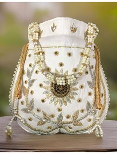 This beautiful Zardosi art work is eye catchy and made of premium material, embellished with Golden Zardosi flower in the center. Material used in this bag is: satin silk, thread, zardosi, sequin, pearl handle. It also boasts of a beautiful Pearl beaded drawstring Tassel. This potli is good match with both Indian and western outfits and are superb for wedding and festive parties. This would be best complement to your designer saree, lehnga or any other kind of dress. This is the combination of t Traditional Handwork Potli Bag For Diwali, Traditional Diwali Potli Bag With Handwork, Traditional Gold Bag For Navratri, Traditional Gold Bags For Navratri, Traditional Zari Work Potli Bag As Gift, Bollywood Style Handmade Potli Bag For Festivals, Diwali Gold Potli Bag With Pallu, Traditional Gold Potli Bag For Navratri, Gold Potli Bag With Pallu For Festivals