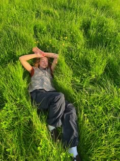 a man laying in the grass with his hands on his head