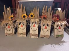 some scarecrows made out of wood sticks and sunflowers are sitting on the table