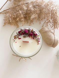 a candle with flowers in it next to some twine and other items on the table