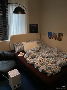 a bed sitting next to a black couch in a living room under a light fixture