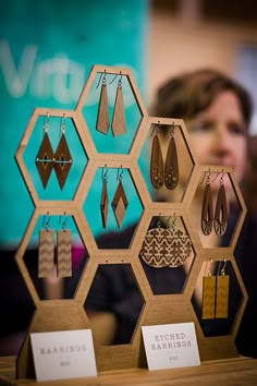 a woman looking at earrings on display in front of a wall with hexagons